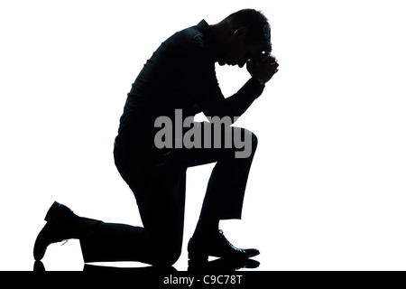 one caucasian man kneeling sadness praying full length silhouette in studio isolated white background Stock Photo