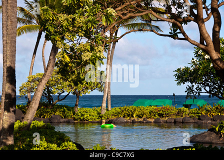 Kauai, Hawaii, woman floating in quiet pond beside the beach Stock Photo