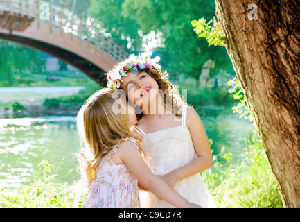 kid girls playing in spring outdoor river park whispering ear Stock Photo