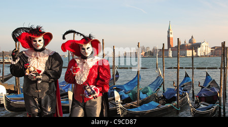 Two participants in traditional venetian carnival costumes against Grand Canal and San Giorgio Maggiore church in Venice, Italy. Stock Photo