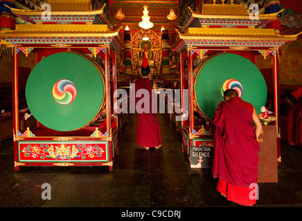 India, South Asia, Sikkim, Buddhist Lama Monks in a ritual inside a monastery beside large drums. Stock Photo