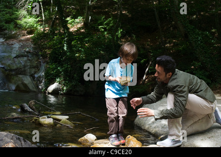 Father and son exploring nature, boy holding rock Stock Photo