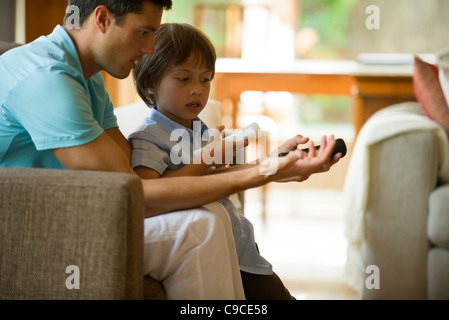 Father and son playing video game using wireless controllers Stock Photo