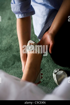 Putting silver wedding shoe on bride's foot. Stock Photo
