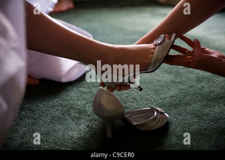 Putting silver wedding shoe on bride's foot. Stock Photo