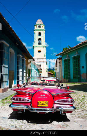 Cuba, Caribbean, Sancti Spiritus, Trinidad, Red 1957 Chevrolet convertible car parked in cobbled street with bell tower distant Stock Photo