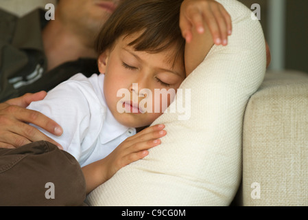 Boy napping on sofa with his father, cropped Stock Photo