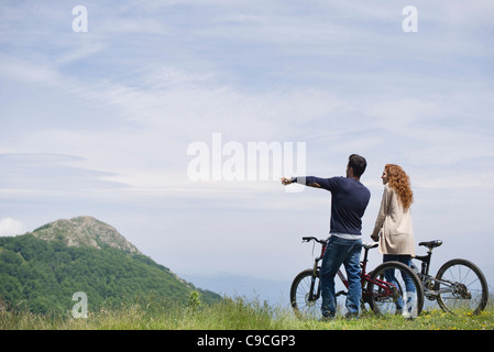 Couple standing by mountain bikes enjoying scenic mountain view Stock Photo
