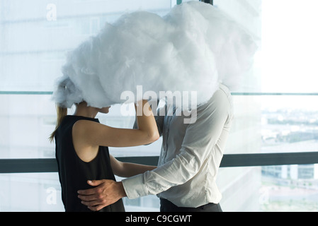 Businessman and businesswoman embracing behind cloud Stock Photo