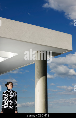 Fashionably dressed young woman contemplating view from portico Stock Photo