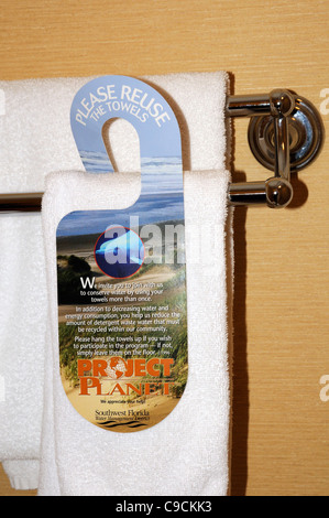 Hotel towels & hanging sign requesting guests to use their towel more than once to conserve water & energy Stock Photo