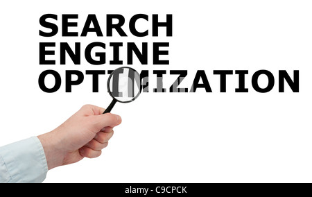 SEO - Man's Hand With Magnifying Glass on Search Engine Optimization Sign - Isolated on White Stock Photo