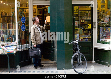 A man searches for a book outside a shop in Cecil Court, London, UK Cecil Court specialises in rare and antiquarian bookshops Stock Photo