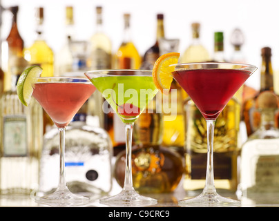 Assorted martini cocktails with bottles of liquor in the background Stock Photo