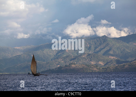A traditional malagasy sailing outrigger boat with a full sail off Mamoko island in north-western Madagascar, near Nosy-Be. Stock Photo