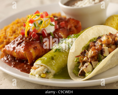 A chicken taco, burrito and seafood enchilada served with Spanish rice and black beans on a white plate Stock Photo