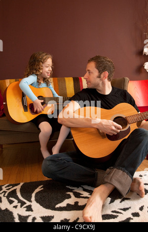 Father and daughter playing the guitar. Stock Photo