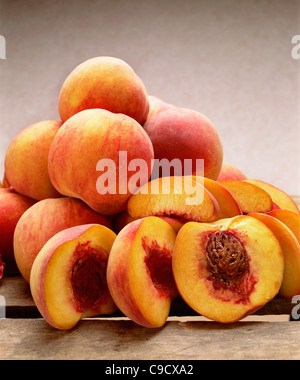 Yellow freestone peaches whole and halved showing stone. Stock Photo