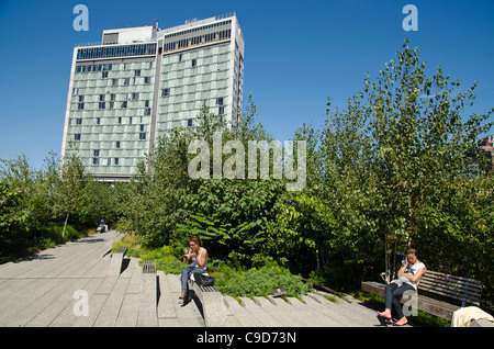 USA, New York, Manhattan, West Side, High Line Park, people relaxing on benches around 13th street with Standard Hotel beyond. Stock Photo