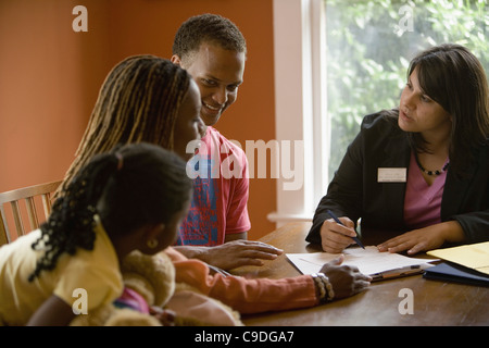Family at home signing papers with agent Stock Photo
