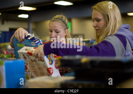 London Ontario, Canada - December 8, 2011. Kaila Swain, left and Emma Beauchamp select toys to create a Christmas toy hamper at the 2011 Salvation Army toy and food drive distribution centre inside the Progress Building at the Western Fair District. This year the Salvation Army expects to provide fo Stock Photo