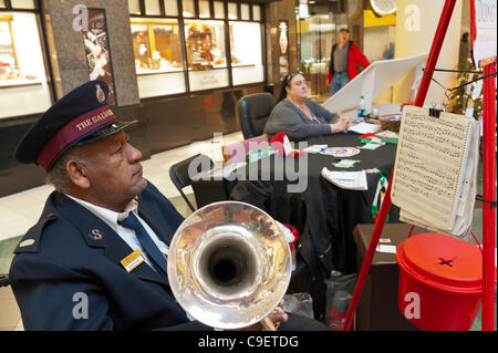 GARDEN CITY, NY, USA - DECEMBER 09: Members of Salvation Army, a charitable and religious organization, raise funds and run Toy Drive at Roosevelt Field Shopping Mall, New York, on Friday, December 9, 2011. Trumpeter Neville Lyttle (left) played for their Red Kettle Christmas Campaign. Stock Photo