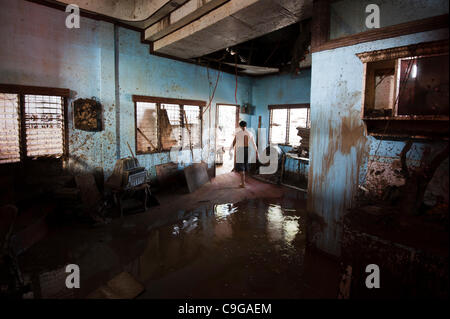 CAGAYAN DE ORO, PHILIPPINES, 22/12/2011. A man clean up after flooding in Cagayan De Oro. Typhoon Washi in the Philippines has killed more than 1000 people, and leave  tens of thousands homeless. Stock Photo