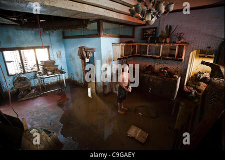 CAGAYAN DE ORO, PHILIPPINES, 22/12/2011. A man clean up after flooding in Cagayan De Oro. Typhoon Washi in the Philippines has killed more than 1000 people, and leave  tens of thousands homeless. Stock Photo