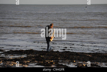 A man playing the saxophone on Eastbourne beach UK Stock Photo