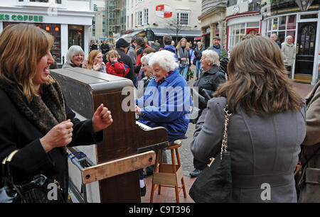 A group of ladies enjoy an impromptu sing song and dance as they borrow a buskers piano in The Lanes area of Brighton Stock Photo