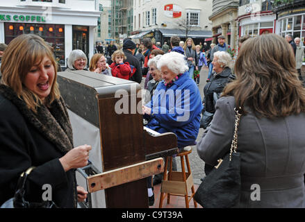 A group of ladies enjoy an impromptu sing song and dance as they borrow a buskers piano in The Lanes area of Brighton Stock Photo