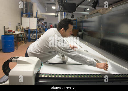 London Ontario, Canada - March 5, 2012. Jose Garcia trims away excess material after panels have been cut by a CNC cutter. These panels are used as templates in the construction of each racing skull. Stock Photo