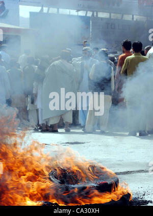 Supporters of Hazara Democratic Party (HDP) gather near burning tyres as they are protesting against target-killing of Hazara community in Quetta on Thursday, March 29, 2012. Atleast six people including a woman were killed in terrorists attack on Thursday, a vehicle was on Stock Photo