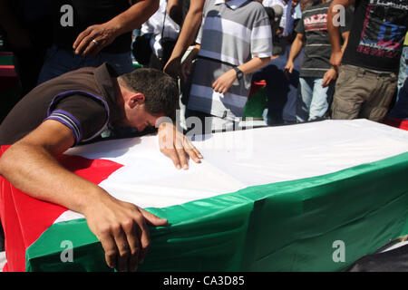 June 1, 2012 - Ramallah, West Bank, Palestinian Territory - Palestinian man mourn over a flag-draped coffin prior to the funeral of 91 Palestinians whose remains were returned by Israel at the Palestinian leadership headquarters in the West Bank city of Ramallah on May 31, 2012. Israel handed over t Stock Photo