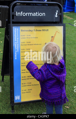 02 June 2012. Hampton Court, England, UK. Girl in front of information board at The Jubilee Garden Party at Hampton Court Palace. Stock Photo