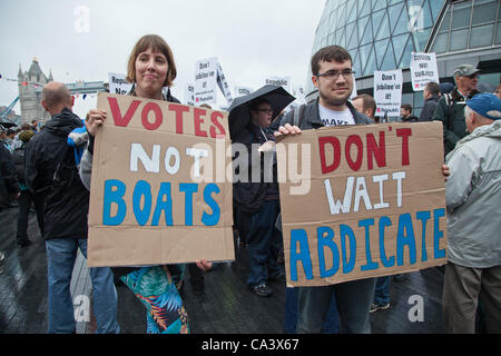 London, UK. 3rd June 2012 Members of the republic group gold up sign saying 'votes not boats', they were with protestors from the Group Republic gathered on the banks of the Thames outside the City Hall to protest against the monarchy on the day of the Thames Diamond Jubilee pageant. Stock Photo