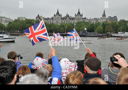 3rd June 2012. Southbank, London, UK. Crowds of people enjoying the Pageant on the Thames and waving flags as they see the boats as they pass down the river. Stock Photo