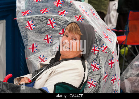 Brenda Allen from Bury, England shelters from rain beneath patriotic Union Jack umbrella, on Tower Bridge, during Queen’s Thames Diamond Jubilee Pageant, London, UK, 3rd June 2012. The Diamond Jubilee celebrates Queen Elizabeth the second’s 60 years as Head of the Commonwealth Stock Photo