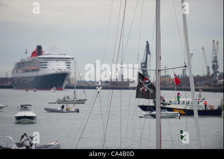 Southampton, UK. The three Cunard cruise ships Queen Elizabeth, Queen Victoria and Queen Mary 2 arrive at Southampton Docks at dawn for the diamond jubilee celebrations on June the 5th 2012. Images shows Queen Mary 2 docked at the Mayflower Terminal with a flotilla of small boats in the harbour. © Stock Photo