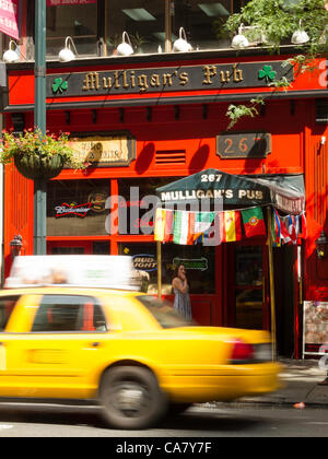 New York City, USA. 24th June 2012.   The UEFA EURO 2012 broadcasts have extended pub hours to accommodate the world time zone differences.  Mulligan's flag display indicates that the tournament is featured on their electronic displays. Stock Photo