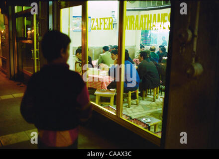 The boy watching the Kurdish men in the tea house will soon join them. At night, in many towns all over Turkey, the men sit and gamble and smoke in tea houses like this one in the eastern city of Diyarbakir. Stock Photo