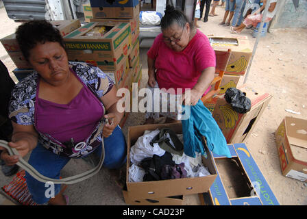 Aug 12, 2010 - Reynosa, Mexico - LUPE RODRIGUEZ a member of the Frank Ferree Group (right) and a local volunteer from Satelite Uno sort and hand out articles of clothing to residents as they leave the food line. (Credit Image: © Josh Bachman/ZUMApress.com) Stock Photo