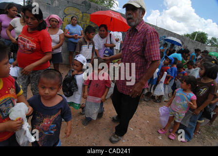 Aug 12, 2010 - Reynosa, Mexico - ROBERTO RODRIGUEZ ushers children into the line towards the distribution point in Satelite Uno. Roberto Rodriguez has been working with the border relief since he was a child, He helped translate for Frank Ferree in the colonia's around Reynosa and after his mother d Stock Photo
