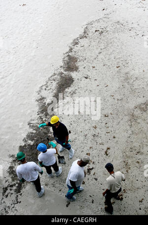 Clean up crews work to scoop up oil on the beach after a break from a thunderstorm in Gulf Shores, Alabama USA on June 5,  2010. Stock Photo