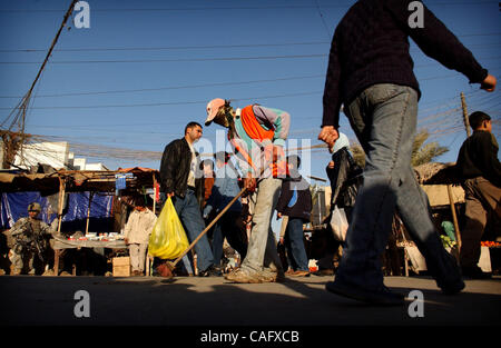 Feb 21, 2008 - Baghdad, Iraq -  Shoppers mill about as a street sweeper cleans up trash in the Fish Market in the Sunni enclave of Shabakar in the Rabi neighborhood of Baghdad. (Credit Image: © Andrew Craft/ZUMA Press) Stock Photo