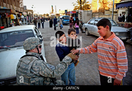 Feb 21, 2008 - Baghdad, Iraq -  Sgt. MICHAEL SCRIVENER, of Bravo Battery, 2nd Battalion of the 319th Airborne Field Artillery Regiment, shakes hands with an Iraqi child during a patrol through the Fish Market in the Sunni enclave of Shabakar in the Rabi neighborhood of Baghdad. (Credit Image: © Andr Stock Photo