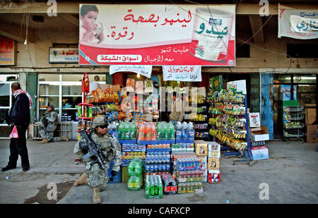 Feb 21, 2008 - Baghdad, Iraq -  Shoppers go about their business as an 82nd Airborne Division paratrooper takes a knee in the Fish Market in the Sunni enclave of Shabakar in the Rabi neighborhood of Baghdad. (Credit Image: © Andrew Craft/ZUMA Press) Stock Photo