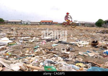 A boy ride  bycle passes a beach covered in flotsam and jetsam that previously was partly mangrove forest, in Jakarta bay on February 16, 2008.. There is less than 150 hectares of mangrove remaining around Jakarta, after authorities in Jakarta launched reclamation programs in the 1980s for developme Stock Photo