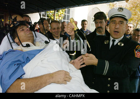 Firefighter Brian Smith, 43, of Ladder Company 44, receives a bottle of Moet Champagne from Ladder Co. 44 Capt. Steven Luisi as he is released from New York-Presbyterian Weill Cornell Medical Center on East 68th Street. Smith fell 30 feet from a ladder bucket while fighting a fire in the Bronx 22 da Stock Photo