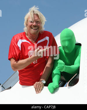 April 4, 2012 - Philadelphia, California, U.S. - Sir Richard Branson (L) and the Green Man from the TV show ''It's Always Sunny In Philadelphia'' greet during a ceremony for the Launch of Virgin America's First Flight from Los Angeles to Philadelphia on Wednesday April 4, 2012 in Philadelphia, Penns Stock Photo